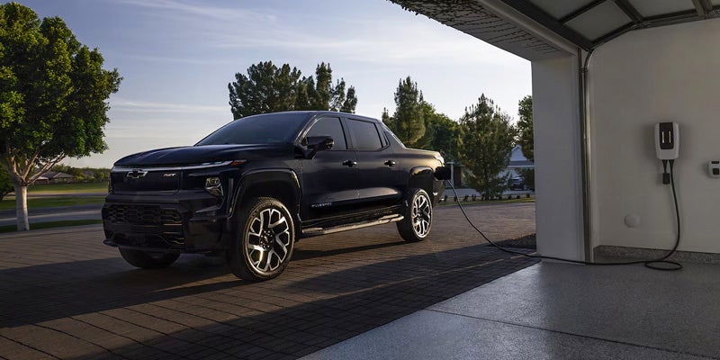 Black 2025 Chevrolet Silverado EV charging outside garage